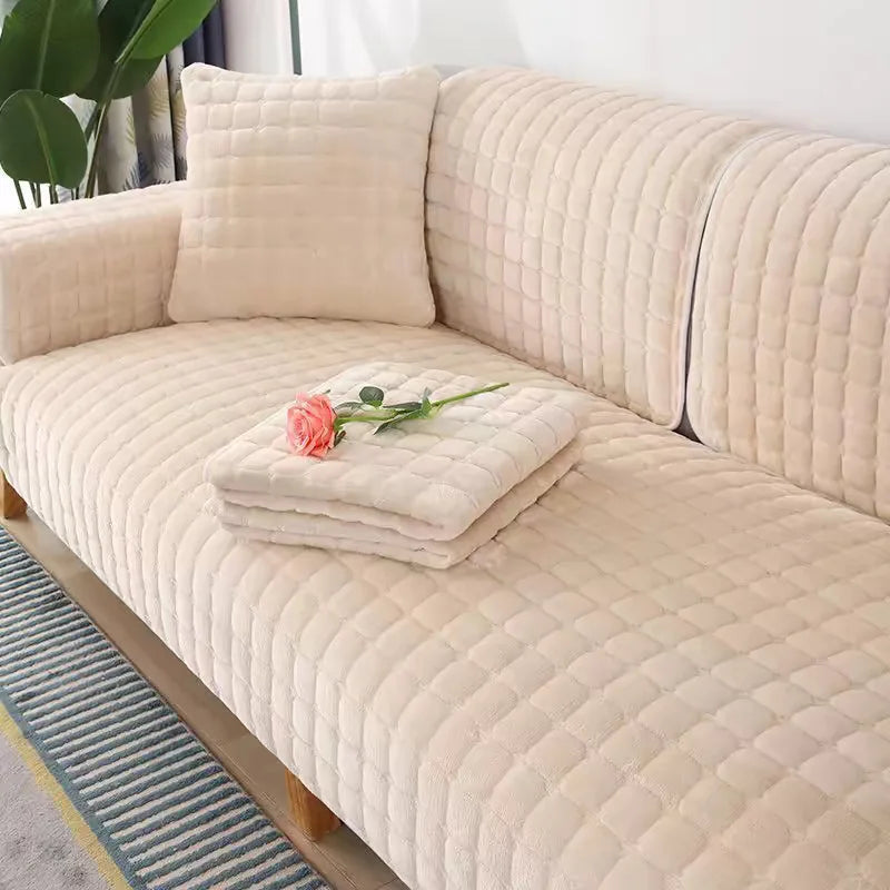 A beige quilted sofa protection cover with a matching pillow and a pink rose decoration.