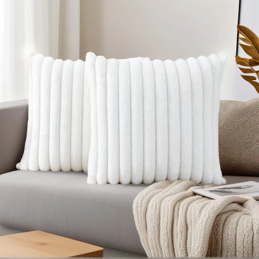 A white, vertically ribbed decorative pillowcase is displayed on a gray sofa.