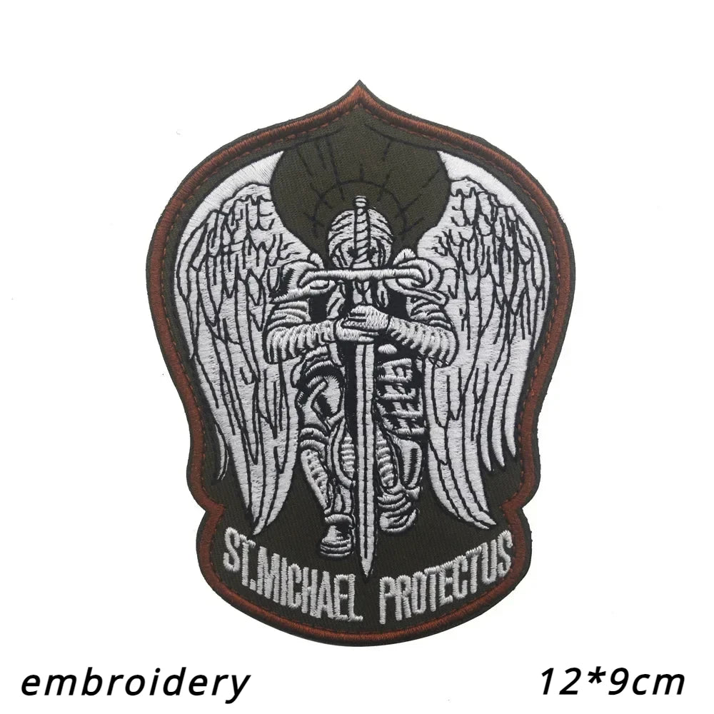 An embroidered patch featuring a winged figure with a sword and the text St Michael Protectus on a dark background.