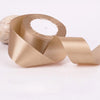 A roll of satin craft ribbon in a beige or champagne color, showing the wide, smooth material.