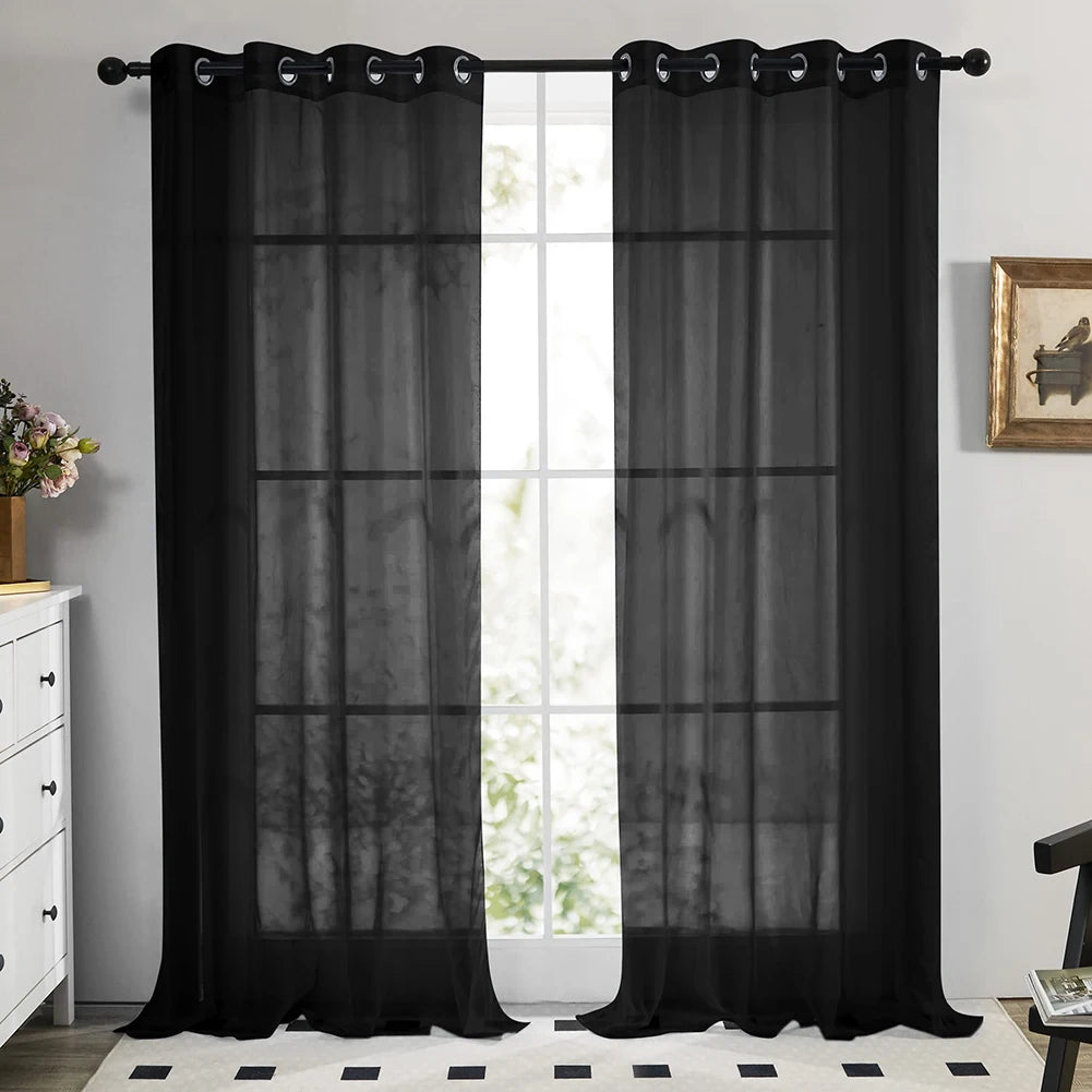 Black sheer tulle window curtains hanging in a doorway with white trim and natural light.