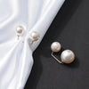 A set of pearl brooch jewelry featuring round pearls on gold-toned pins displayed against a dark background with white silk f