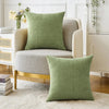 A solid green chenille throw pillow cover resting on a light-colored upholstered sofa.