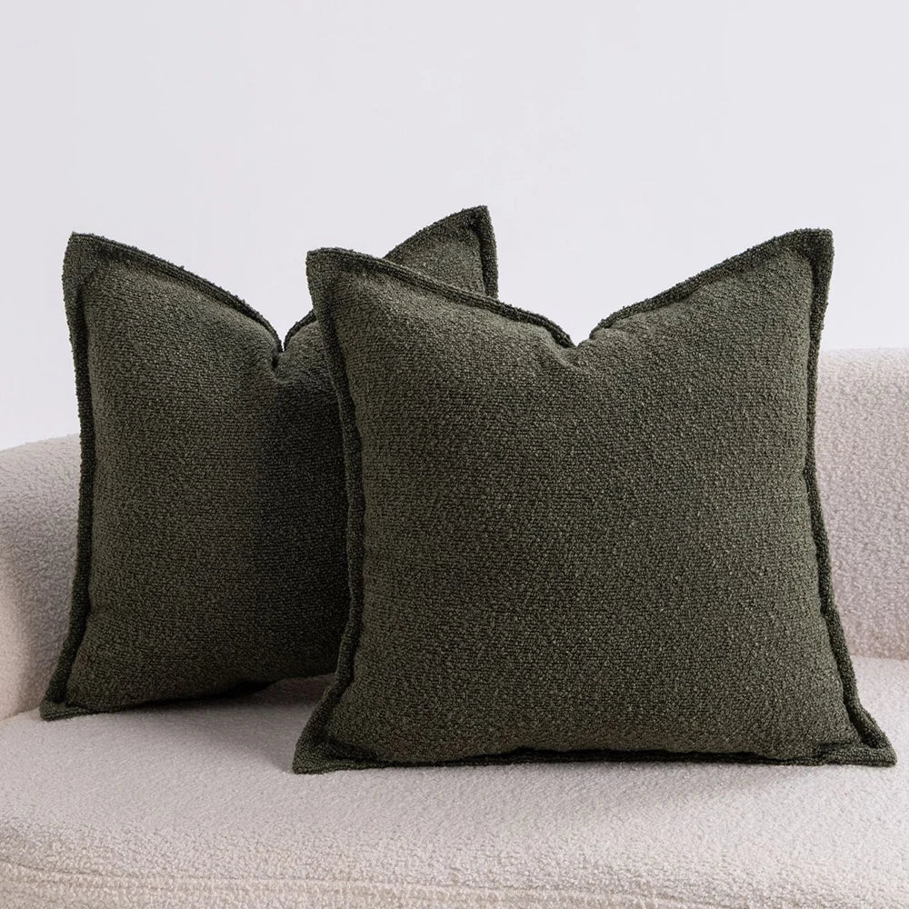 A set of three solid olive green textured boucle throw pillows resting on a light-colored sofa.