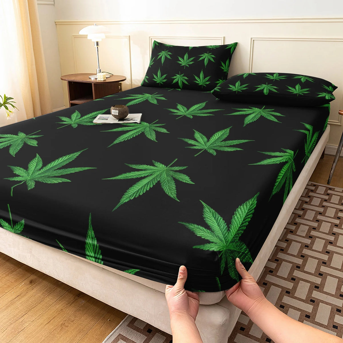 Black fitted sheet with a green hemp leaf print on a bed.