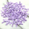 A pile of small lavender satin ribbon bows scattered on a white marble surface.