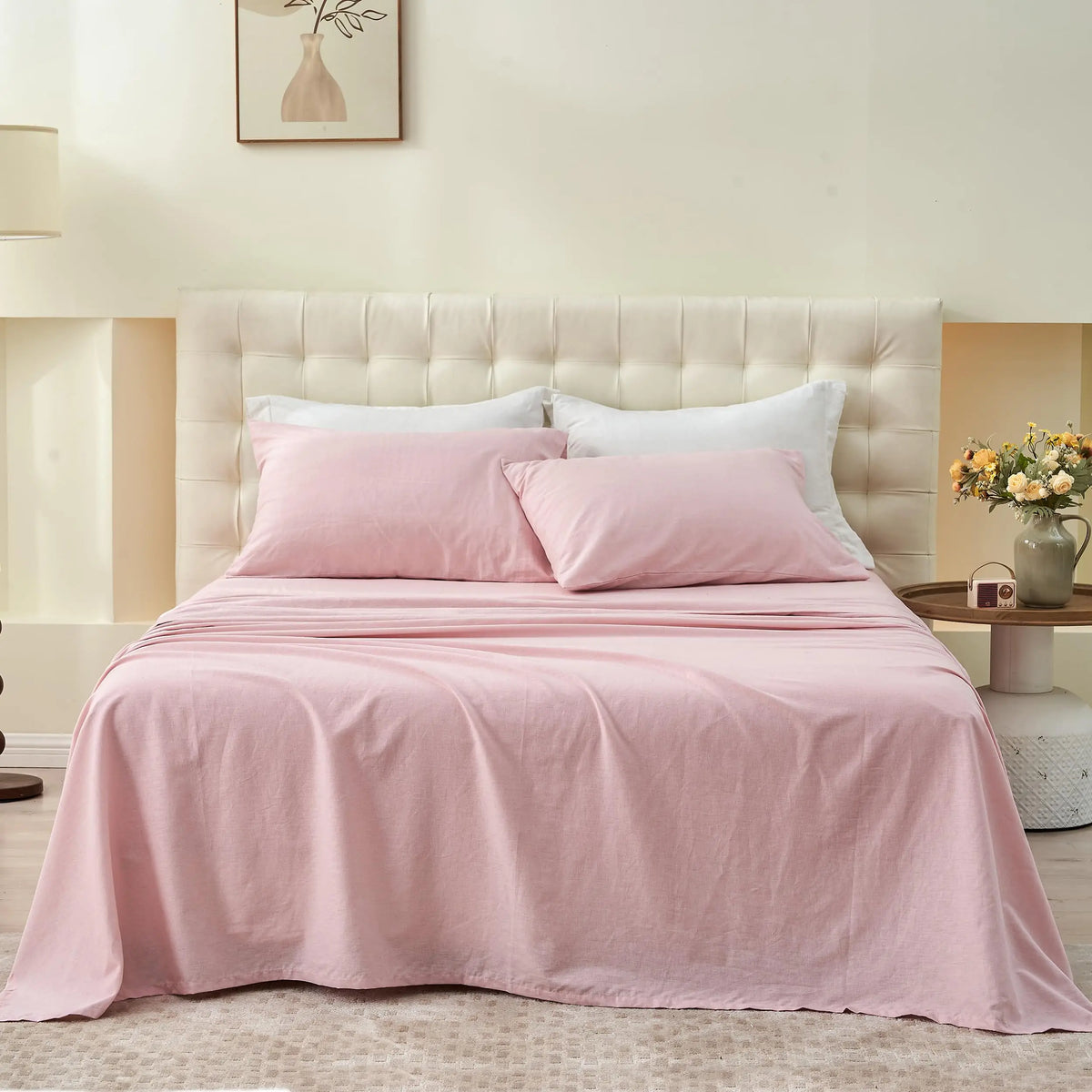 A pink French stone washed linen bedding set with white pillows on a light wood headboard.