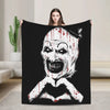 A black throw blanket featuring a white skull design with red splatter and a heart shape.