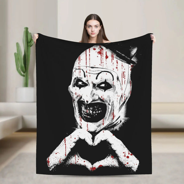 A black throw blanket featuring a white skull design with red splatter and a heart shape.