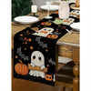 Black Halloween table runner featuring white ghost and pumpkin designs on a wooden table.