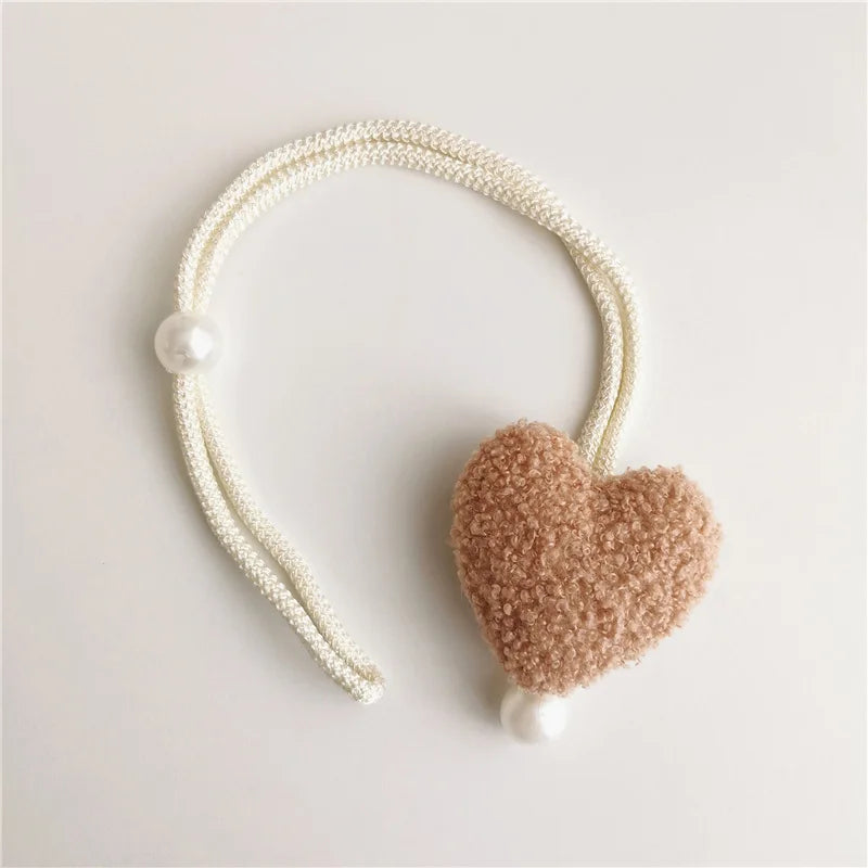 A white pearl beaded tieback with a fuzzy pink heart accent.