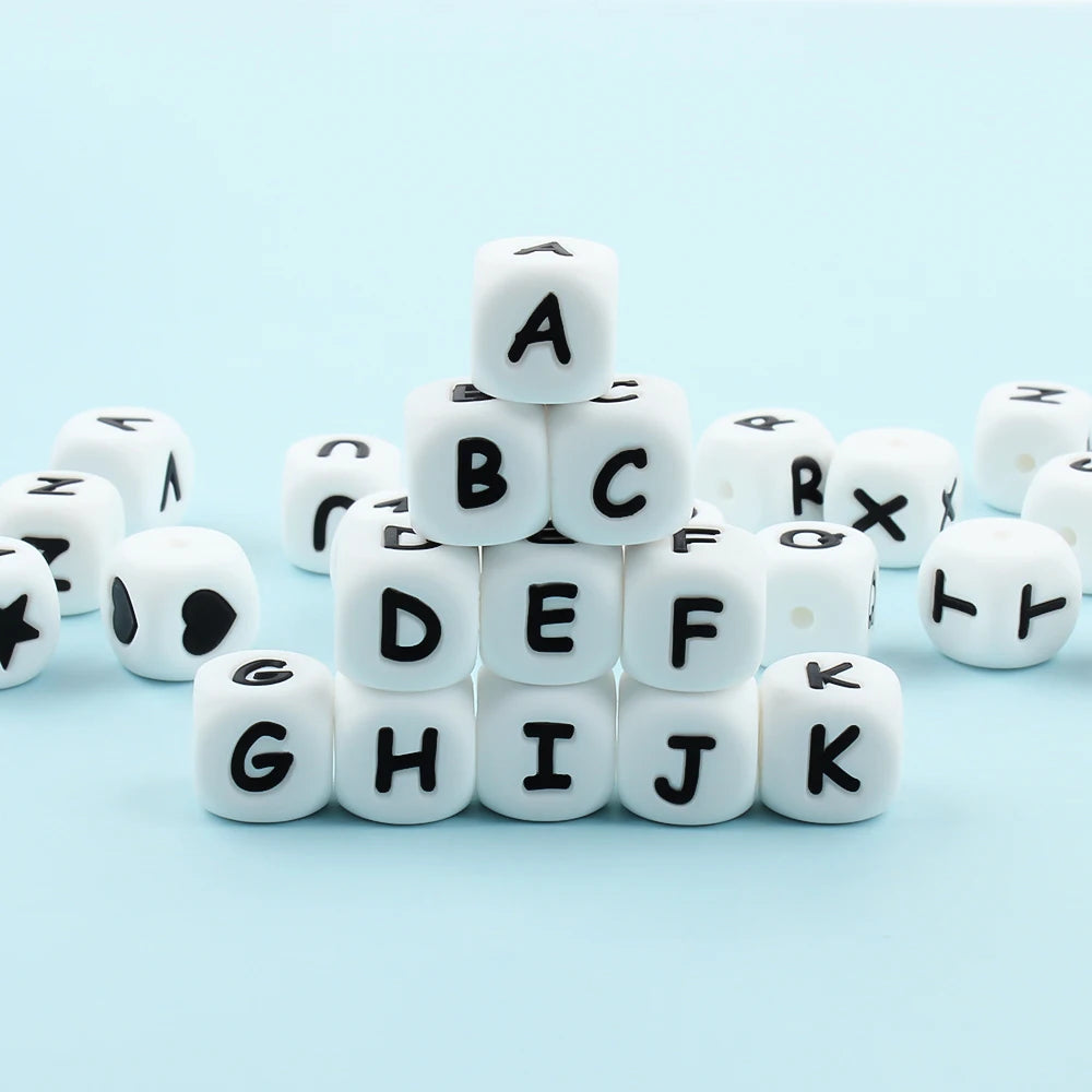 A collection of white alphabet beads A through K arranged in a pyramid shape on a light blue surface.