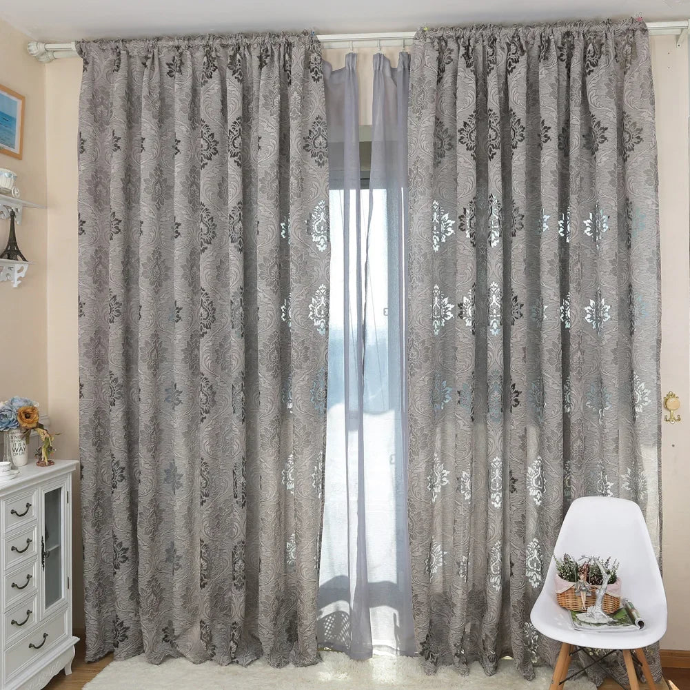 Gray sheer jacquard curtain panels hanging in a window with sheer inner layers