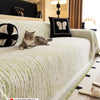 A light green jacquard sofa cover blanket draped over a sofa, with a cat resting on the fabric.