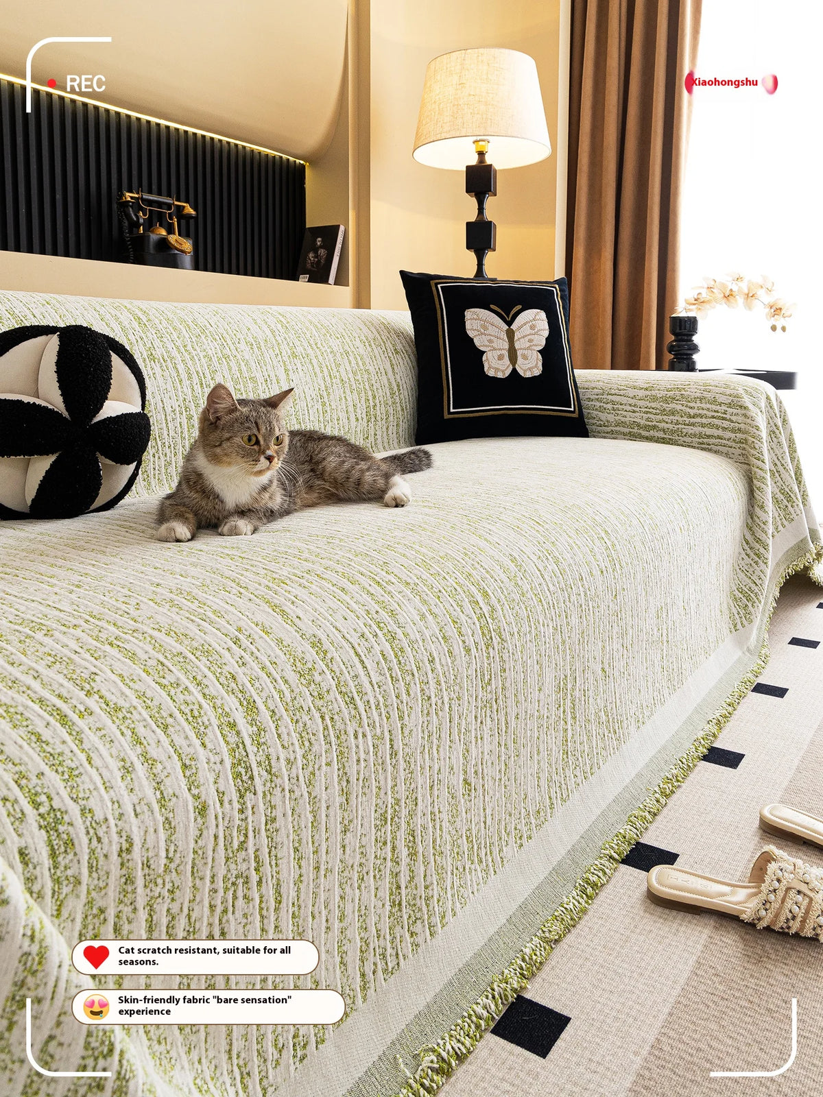 A light green jacquard sofa cover blanket draped over a sofa, with a cat resting on the fabric.