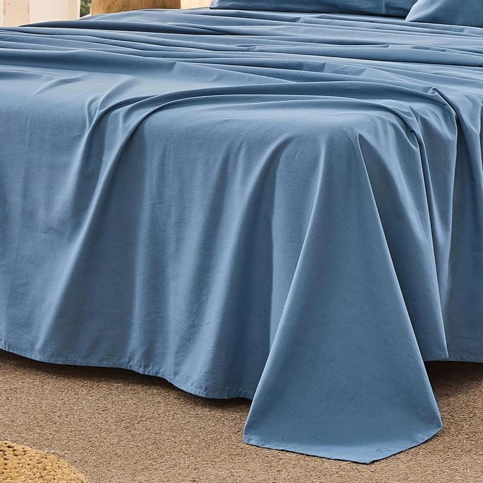A light blue pure French linen bed sheet draped over a bed, shown from the side.