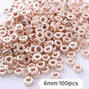 A pile of small rose gold and silver-toned geometric acrylic beads for jewelry making