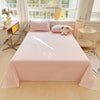 A pink checkered flat sheet and pillow set is displayed on a bed in a bright room with a window view.