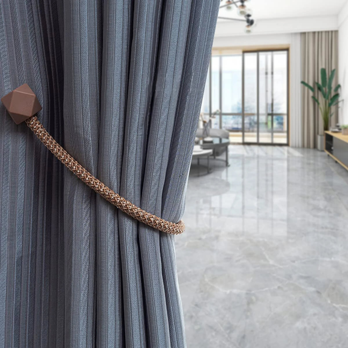 Close-up of a gray pleated curtain with a brass magnetic tieback.