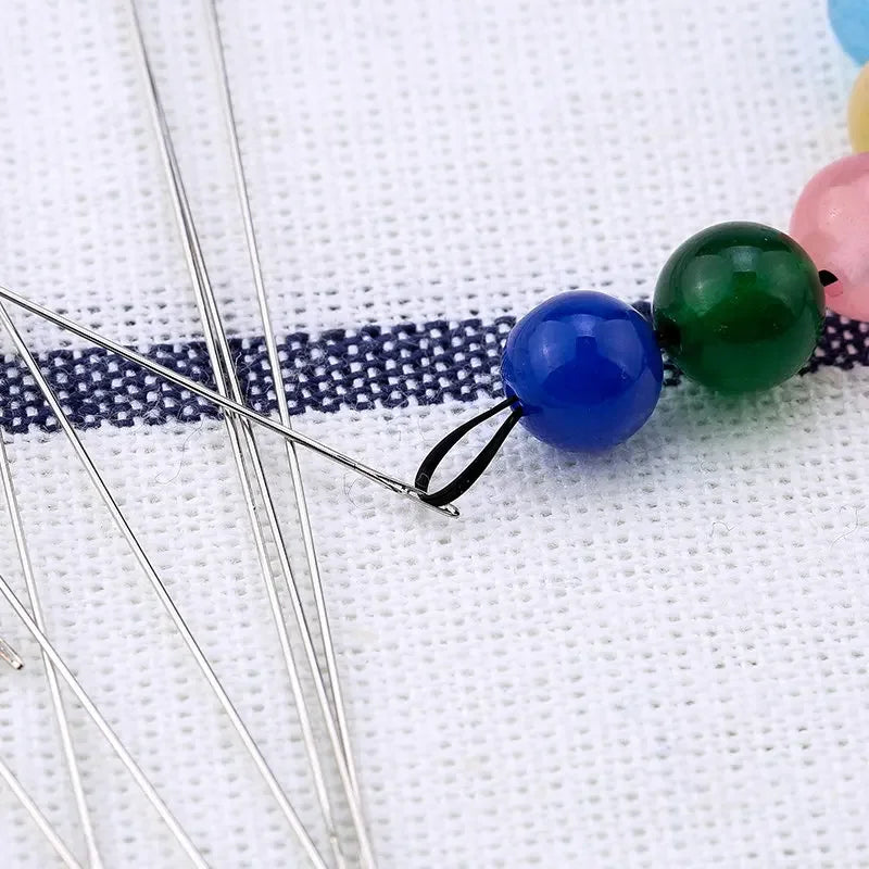 Precision stainless steel beading needles with colorful beads on a white background