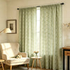 Sage green floral print curtains hanging in a window with natural light filtering through
