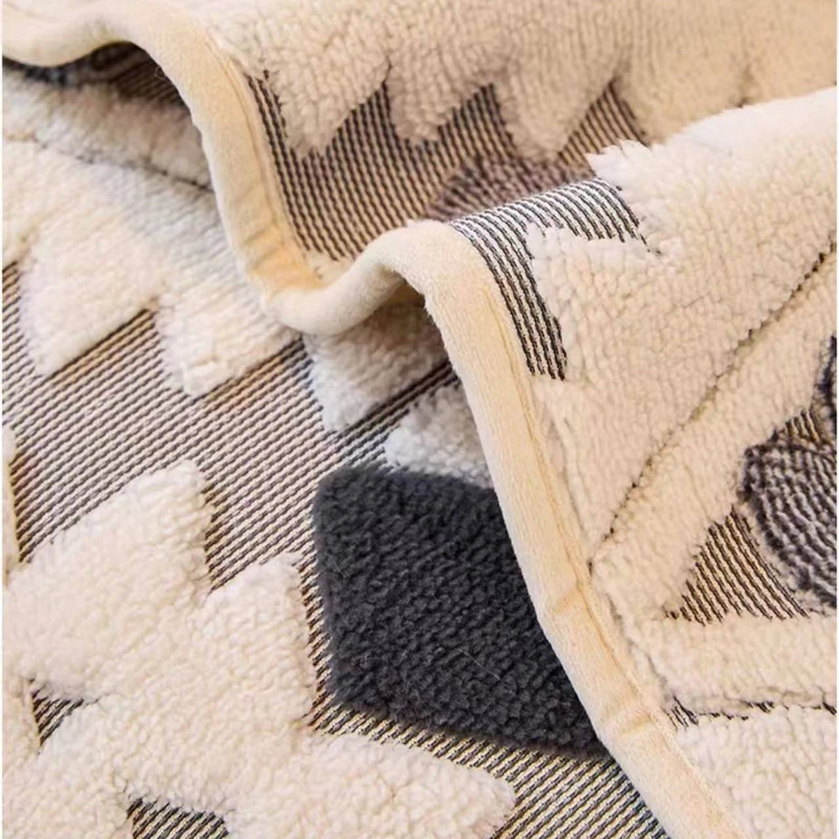 Close-up of a beige and gray patterned fleece fabric showing a folded edge.