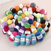 A pile of 12-color soft acrylic yarn balls in various shades of pink, green, yellow, purple, and brown.
