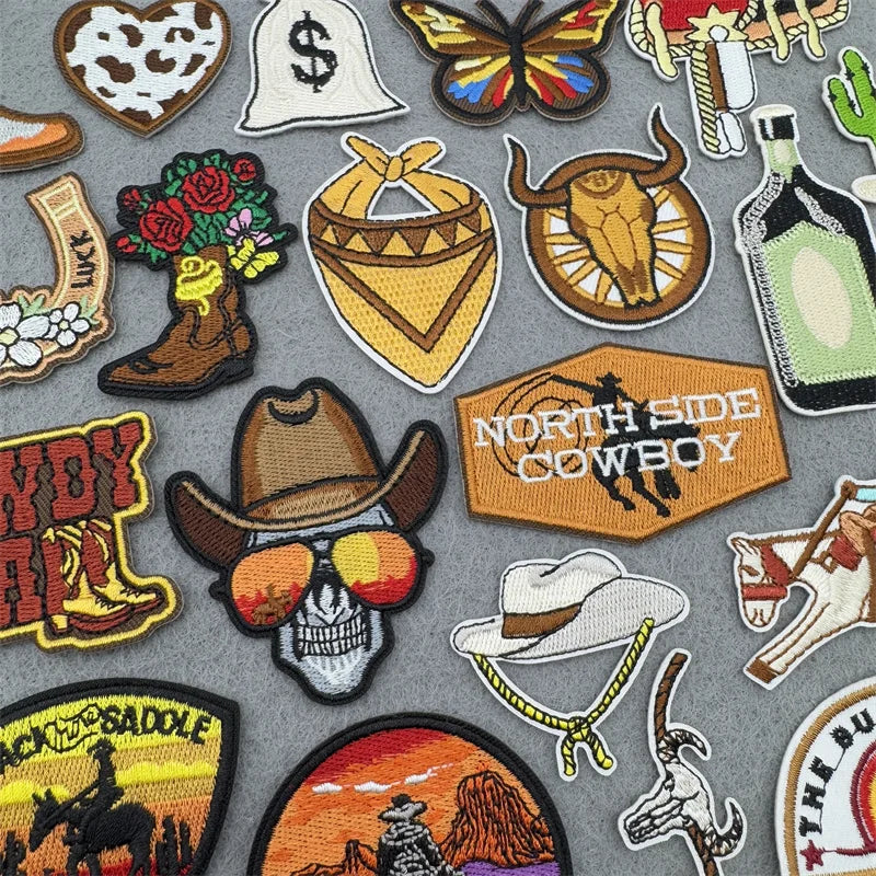 A collection of embroidered iron-on patches featuring various western and cowboy motifs like skulls, bats, boots, and emblems
