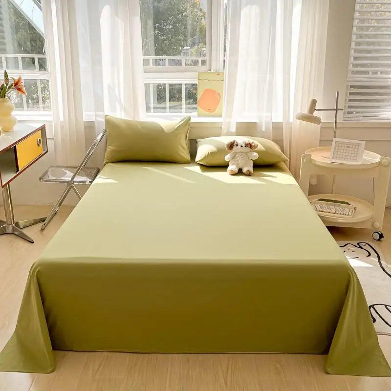 A light green organic cotton bedding set displayed on a bed with white curtains and natural light.