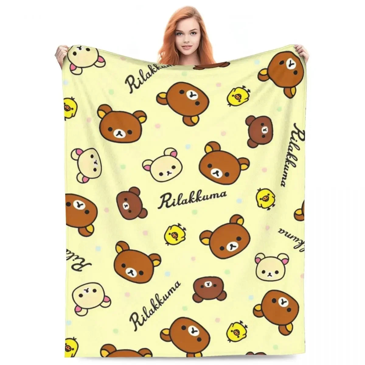 A woman is holding a yellow cartoon plush throw blanket featuring cute brown animal characters and the word Rilakkuma.