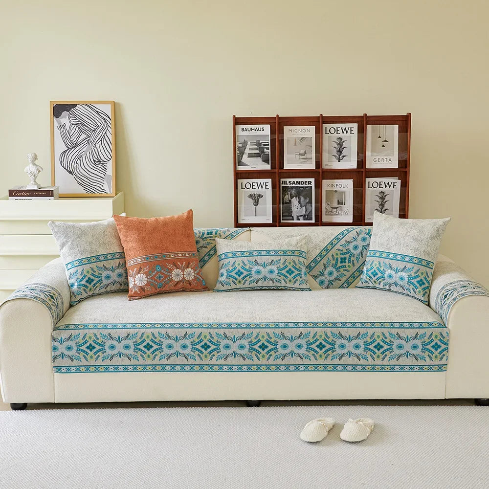 A light beige sofa covered in blue and white patterned chenille fabric with decorative pillows and framed artwork.