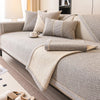 A beige woven sofa cushion cover with light gray accents and a matching throw blanket on a modern sofa.