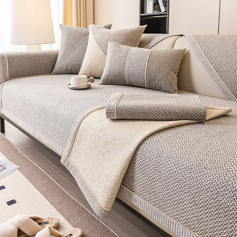A beige woven sofa cushion cover with light gray accents and a matching throw blanket on a modern sofa.