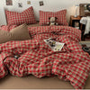 A red and green plaid duvet cover set displayed on a bed with pillows and decorative items.