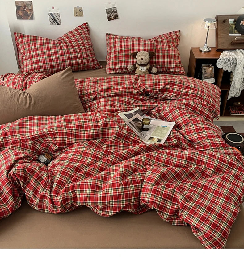 A red and green plaid duvet cover set displayed on a bed with pillows and decorative items.