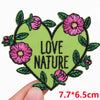A green heart shaped embroidered patch with pink flowers and green leaves.