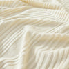 Close-up of a cream-colored stretchable sofa cover with fine vertical line pleats and folds.