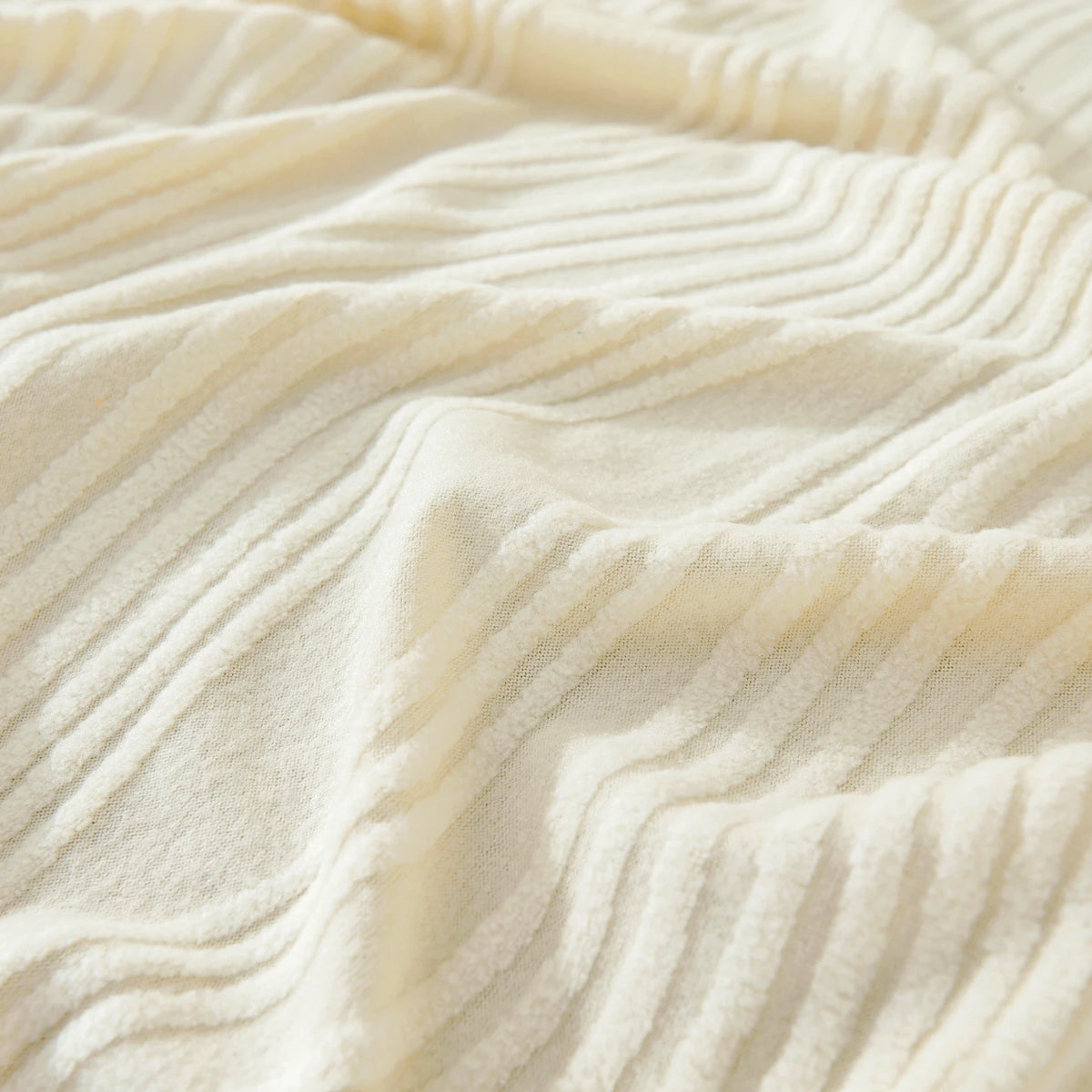 Close-up of a cream-colored stretchable sofa cover with fine vertical line pleats and folds.