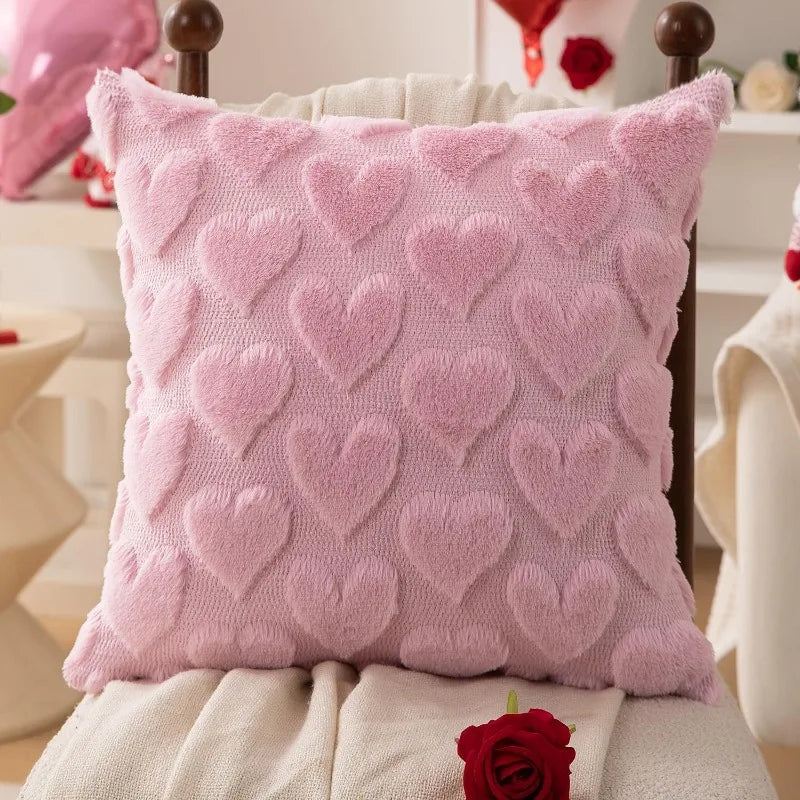 A pink heart embroidery plush cushion cover resting on a white surface.