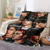 A dark-themed fleece throw blanket featuring multiple portraits of Stray Kids members.
