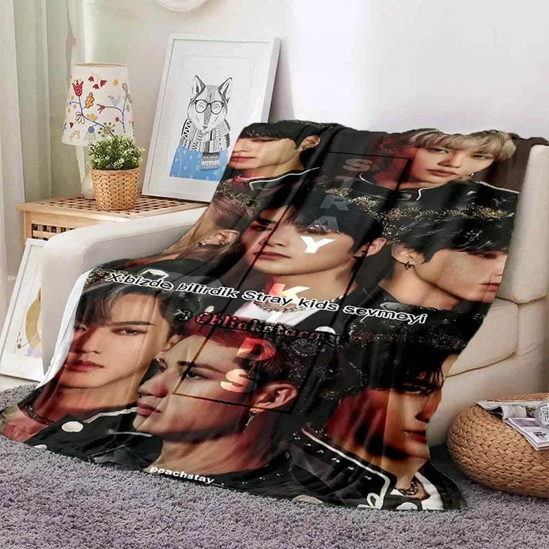 A dark-themed fleece throw blanket featuring multiple portraits of Stray Kids members.