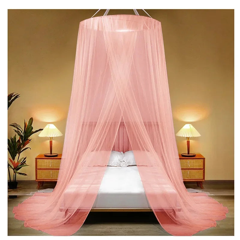 Pink sheer mosquito net canopy draped over a bed in a bedroom setting
