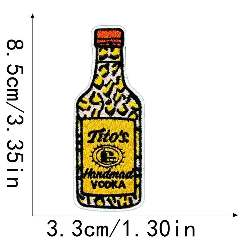 A yellow embroidered iron-on clothing patch shaped like a bottle, featuring the text Tito's Handmade Vodka.