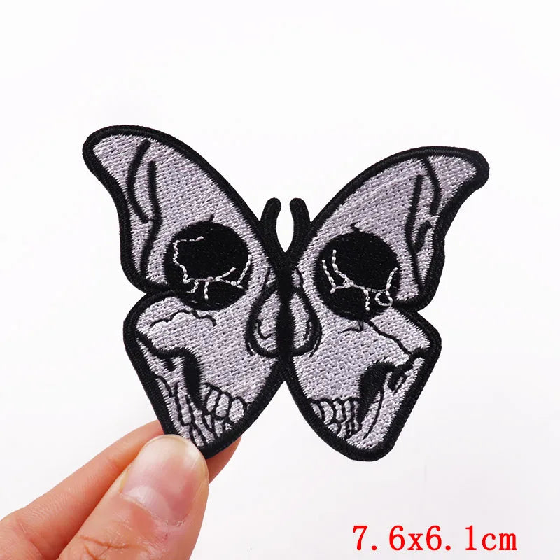 Black embroidered butterfly patch featuring skull designs on a gray fabric