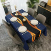 A dark blue rectangular tablecloth set for dining or party decor featuring gold and orange accents.
