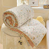 A rolled soft breathable quilt with a floral pattern is displayed on a lace-edged fabric surface.