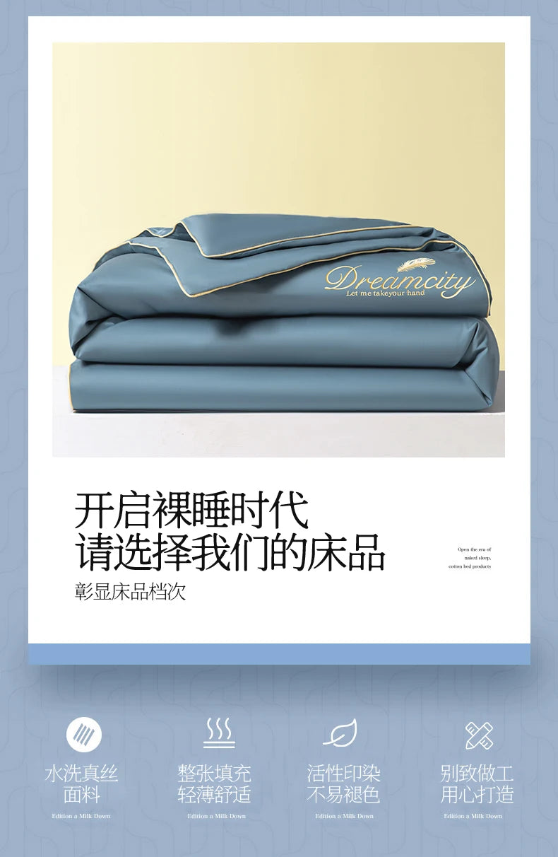 A stack of light blue ice silk fiber quilts with a gold embroidered logo on the cover.