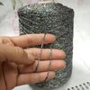 A hand holds a spool of silver glitter metallic yarn for crochet and knitting.