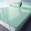 A set of three mint green cooling ice silk sheets folded on a white bed with matching pillows.