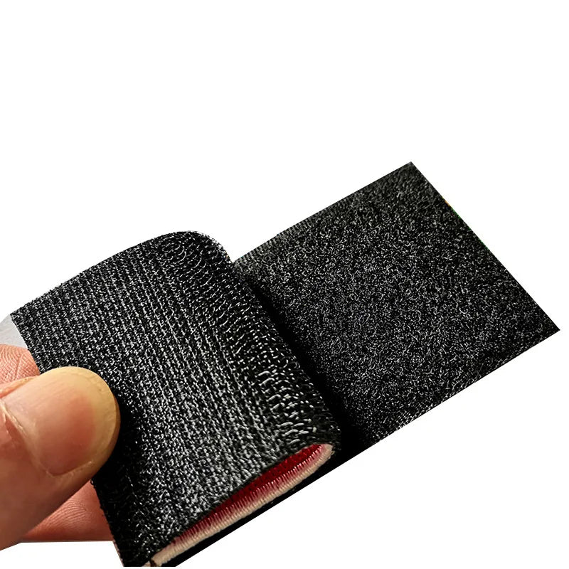 A close-up of a black pirate skull embroidery patch for tactical gear being held by a hand.
